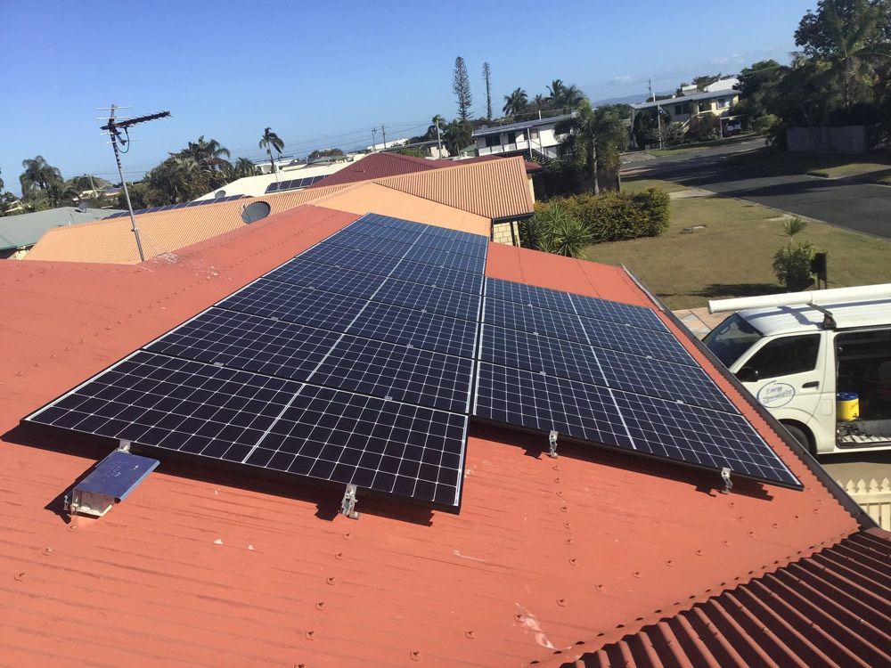 Solar Panels on a Red Roof Under a Clear Blue Sky — Central Solar Services in Garbutt, QLD