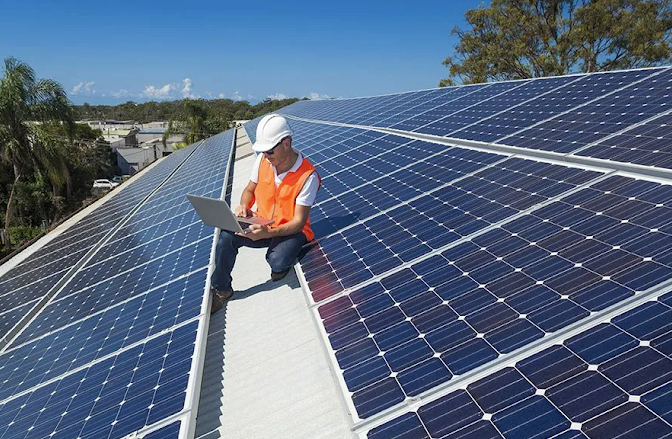 Close-up of solar panel cells installed on a rooftop in Townsville, with gum trees against a blue sky