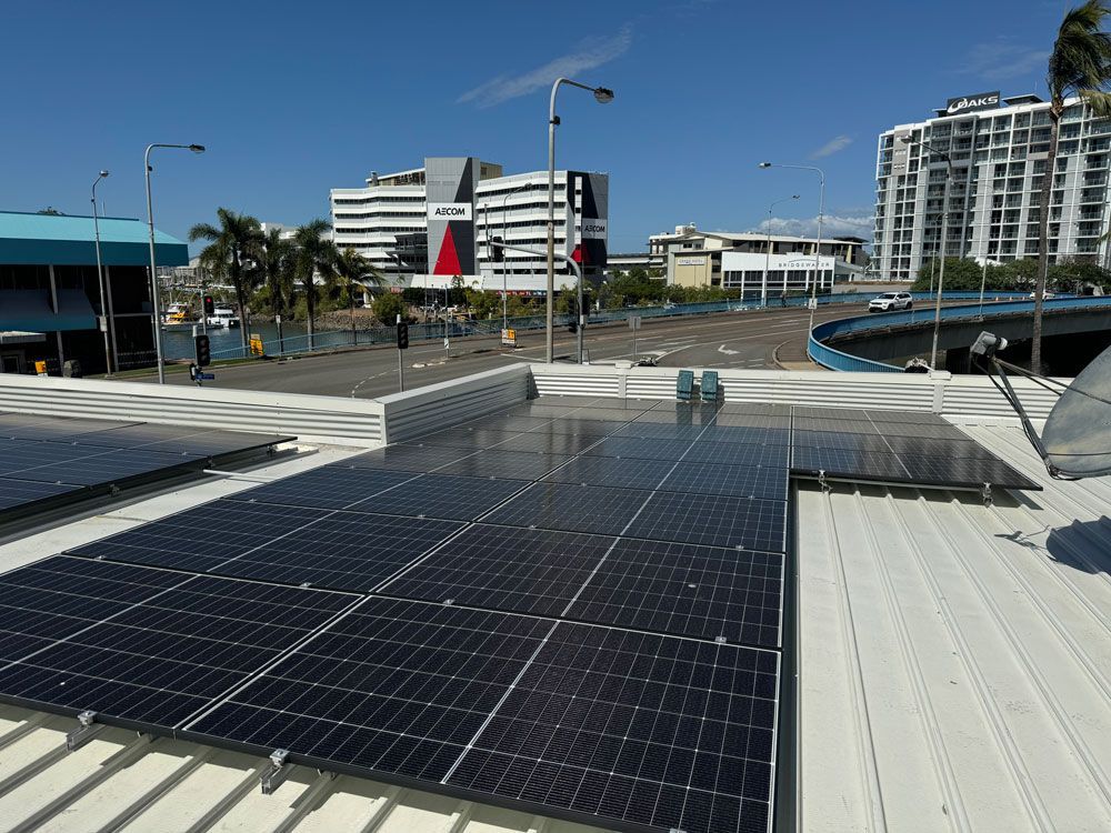 Solar Panels on a Rooftop With City Buildings and Clear Blue Sky in the Background — Central Solar Services in Garbutt, QLD