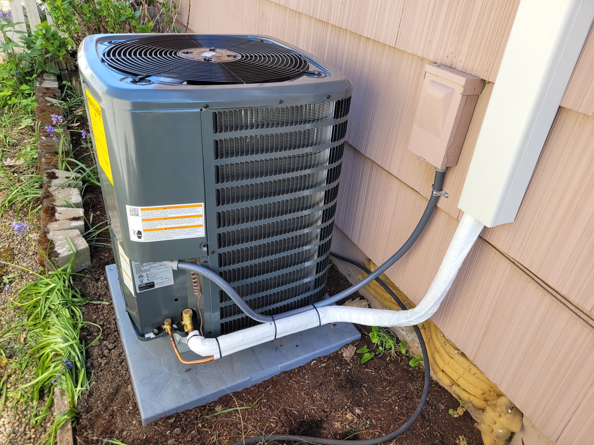 an air conditioner is sitting on the ground next to a house .