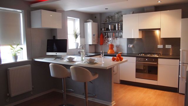 Modern kitchen with white cabinets, gray island, bar stools, and stainless steel appliances