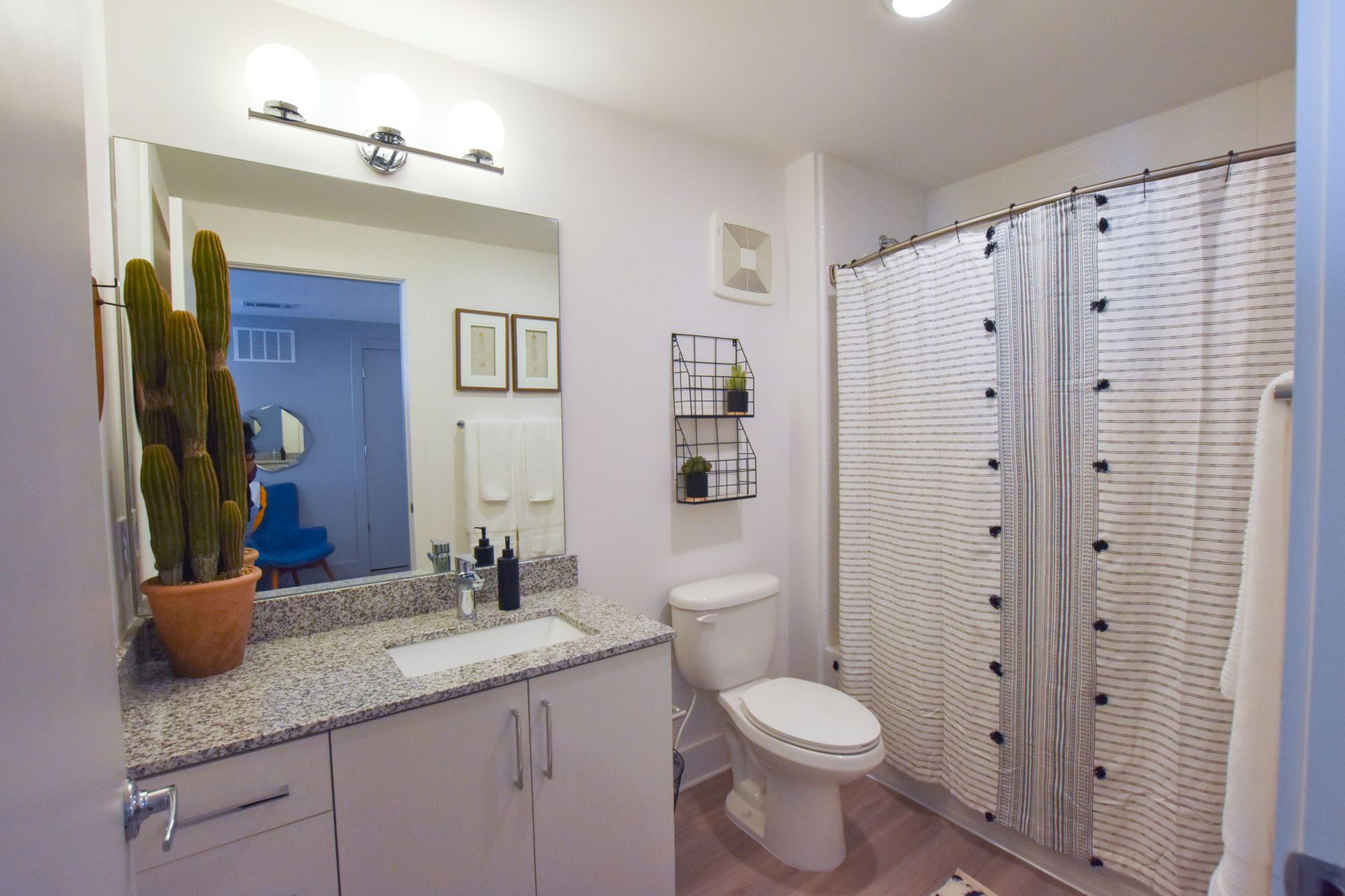 Modern bathroom with granite vanity, wall mirror, toilet, and shower curtain in neutral tones