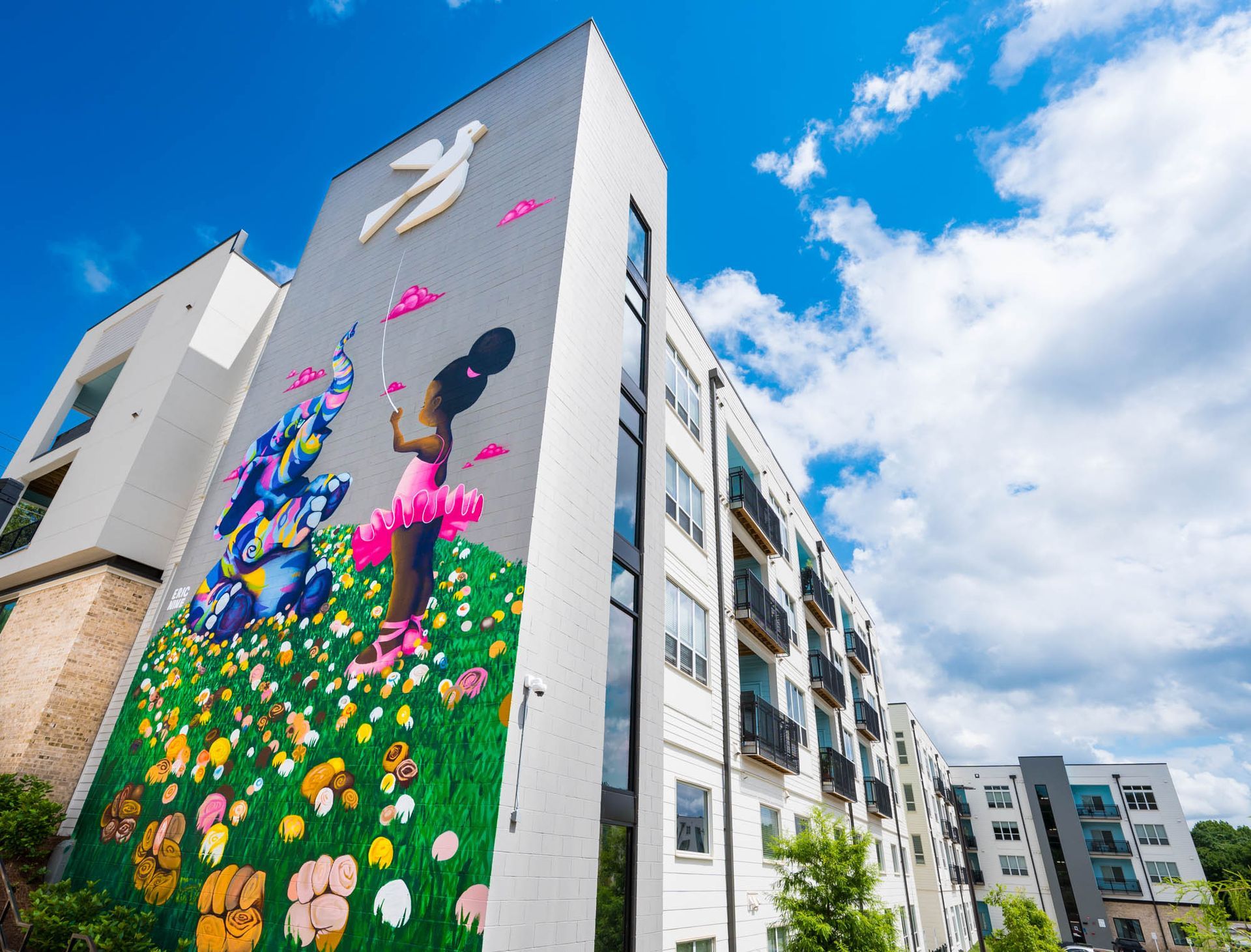 Colorful mural on a tall apartment building beside modern residential towers under a blue sky