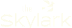 Pale yellow “The Skylark” text logo on a white background with a small bird icon above the wordmark