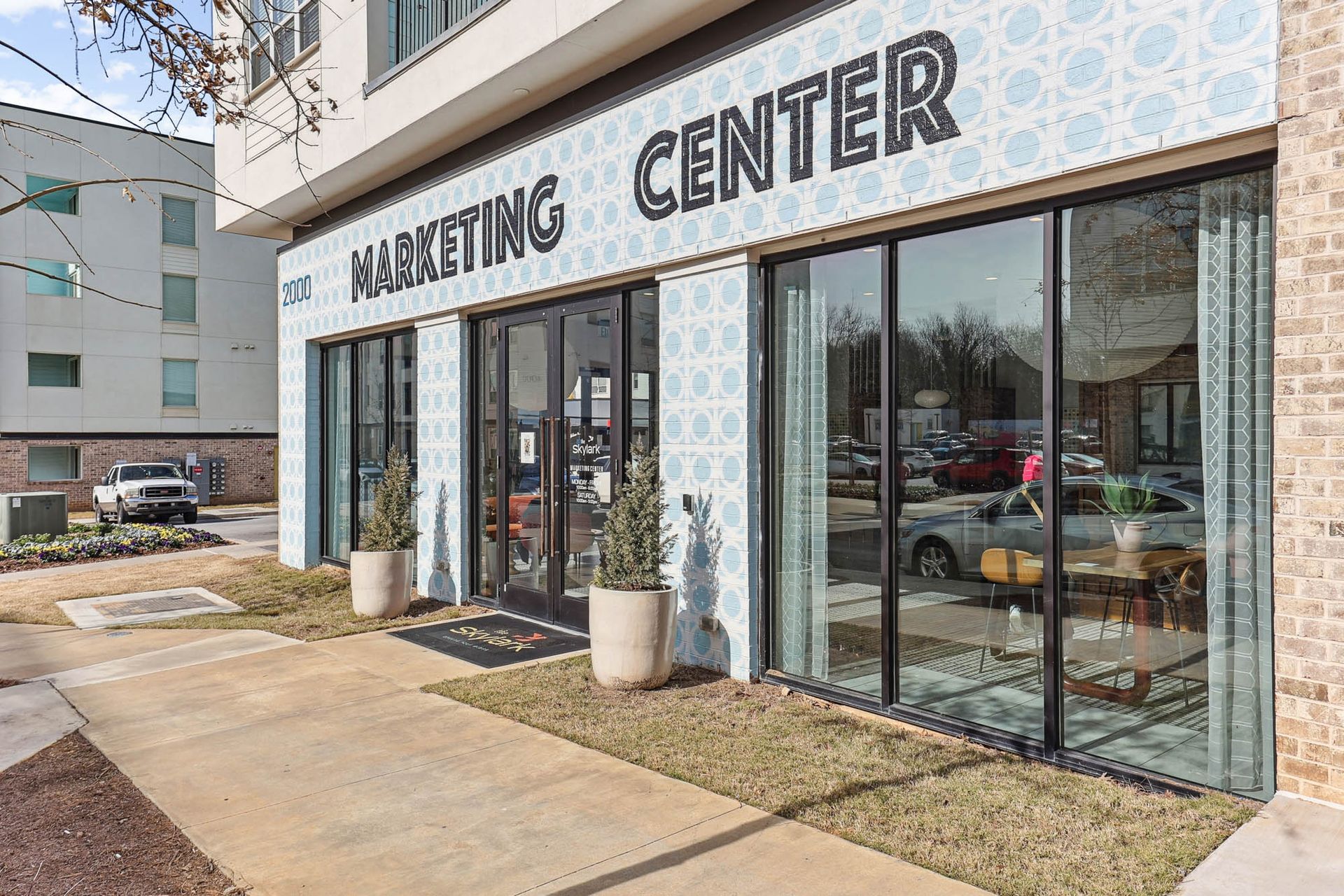 Exterior of a market center with glass storefronts, blue patterned tile, and large signs above the entrance.