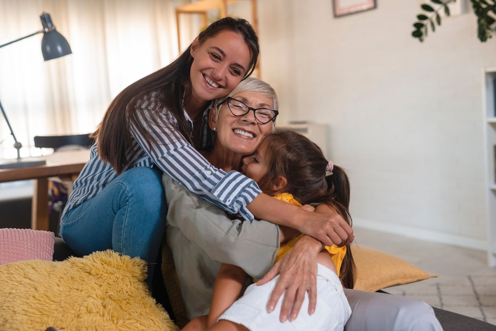 A woman and two children are hugging each other on a couch.