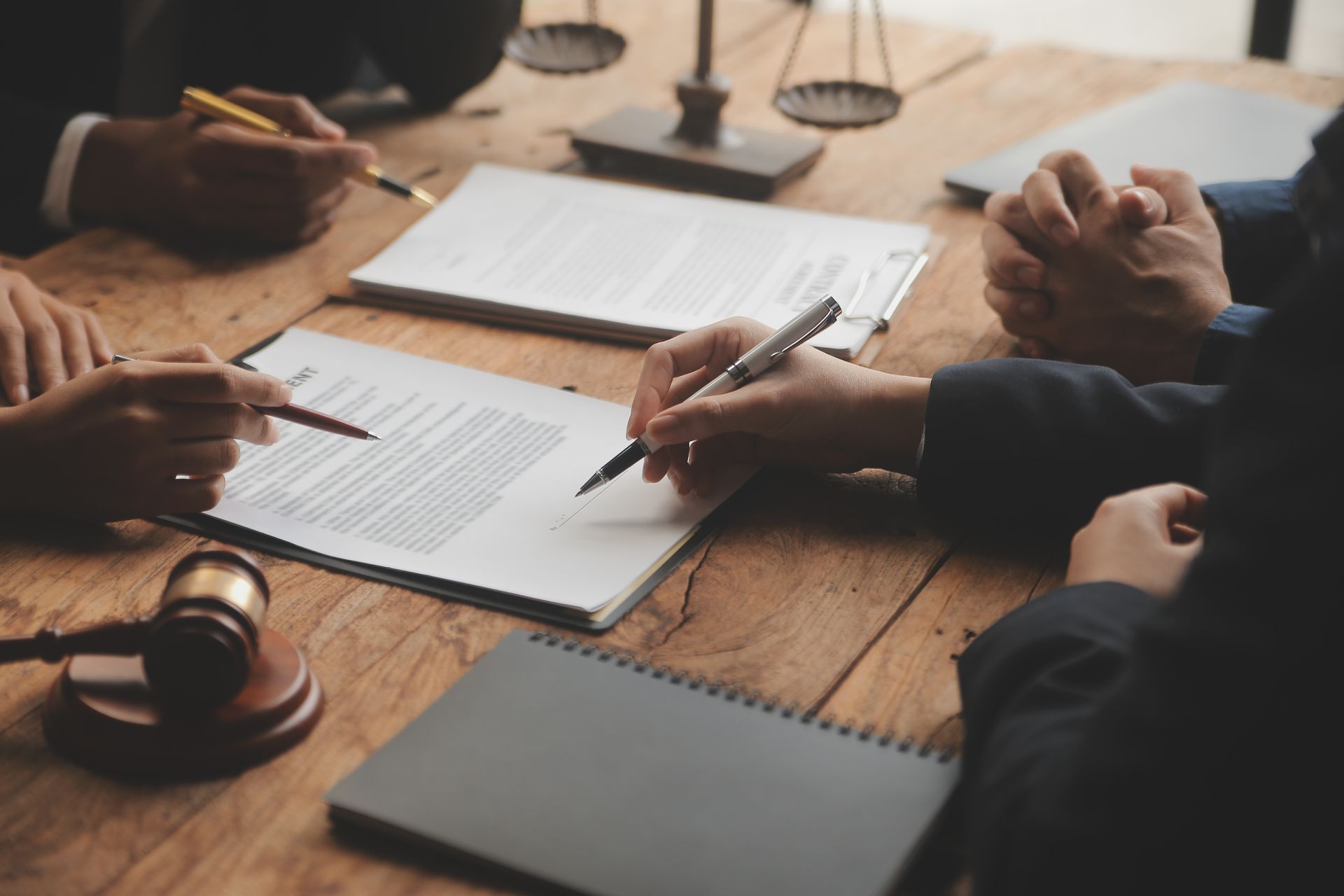A group of people are sitting around a wooden table signing papers.