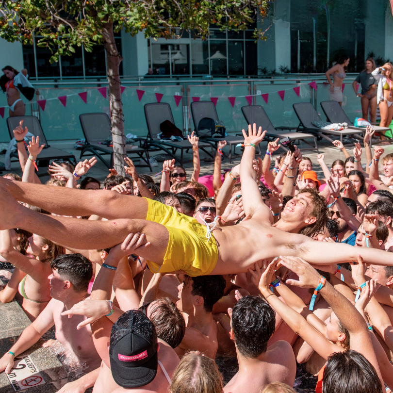 A man in yellow shorts is being lifted in the air by a crowd of people