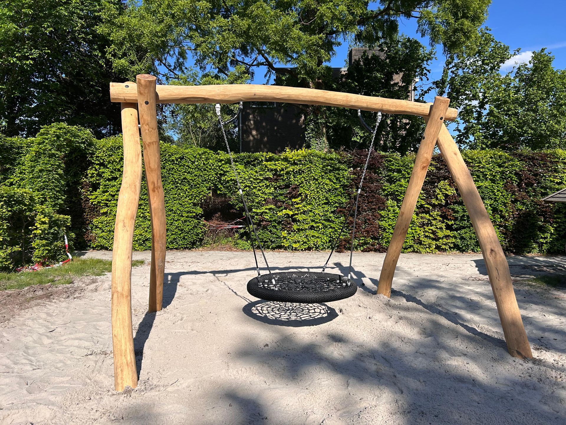 Zwarte rechthoekige trampoline met veiligheidsnet op een grasveld.
