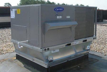 A carrier air conditioner is sitting on top of a gravel covered roof