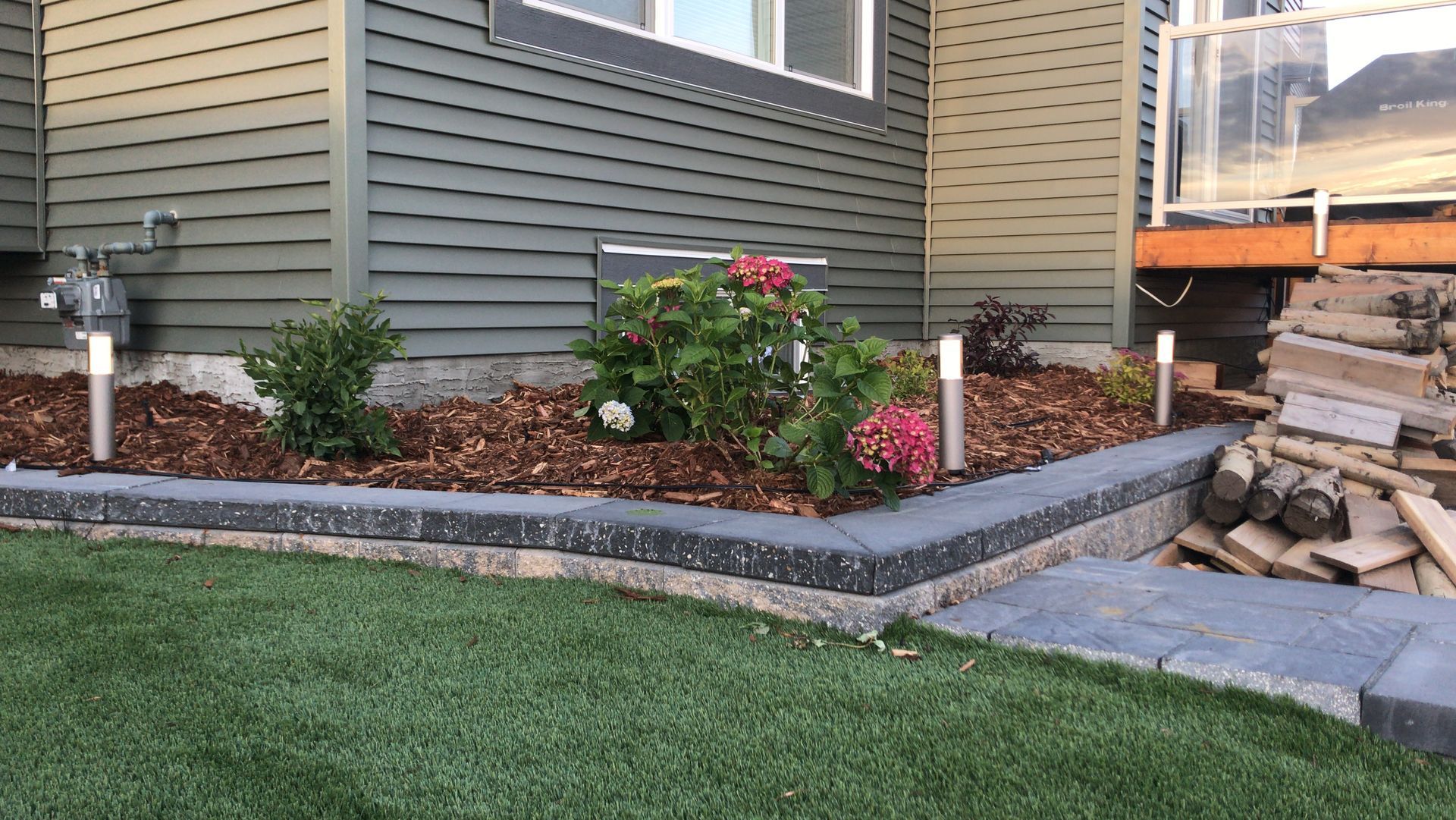 stone edged garden bed with mulch and flowers