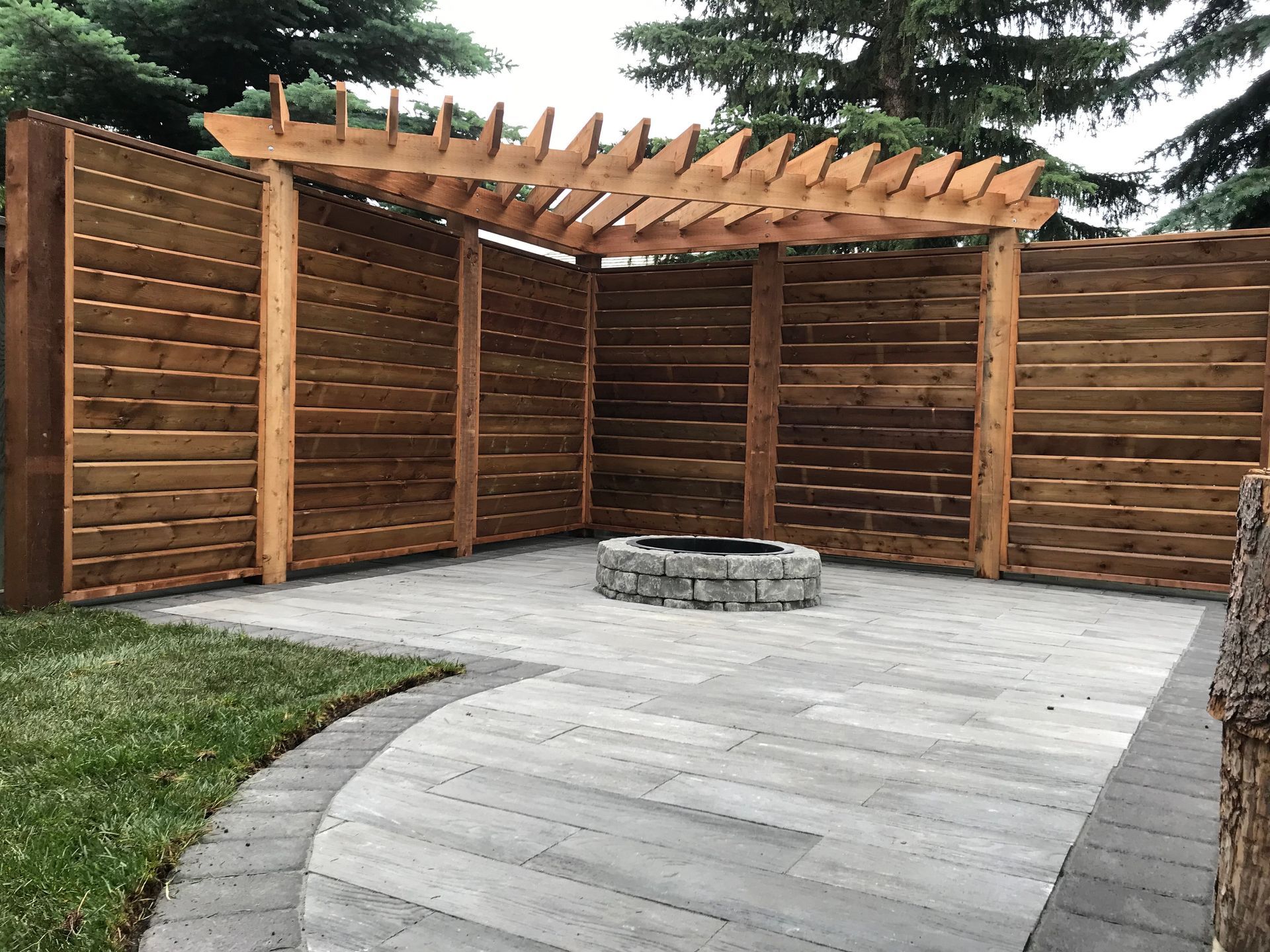 built in stone fire pit with wood pergola nearby