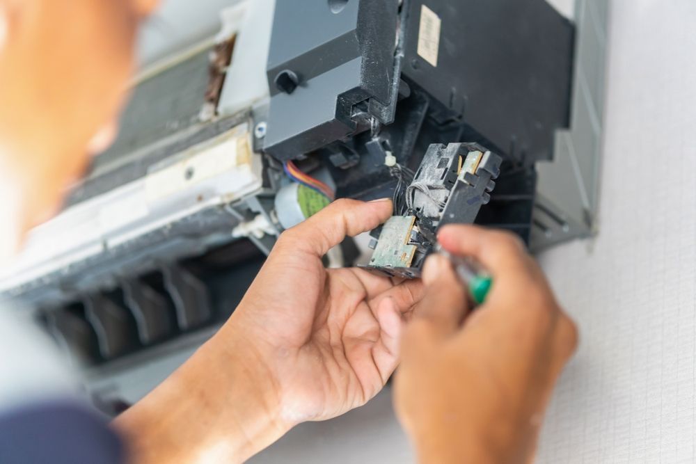 Technician repairing electrical wiring inside an air conditioner unit