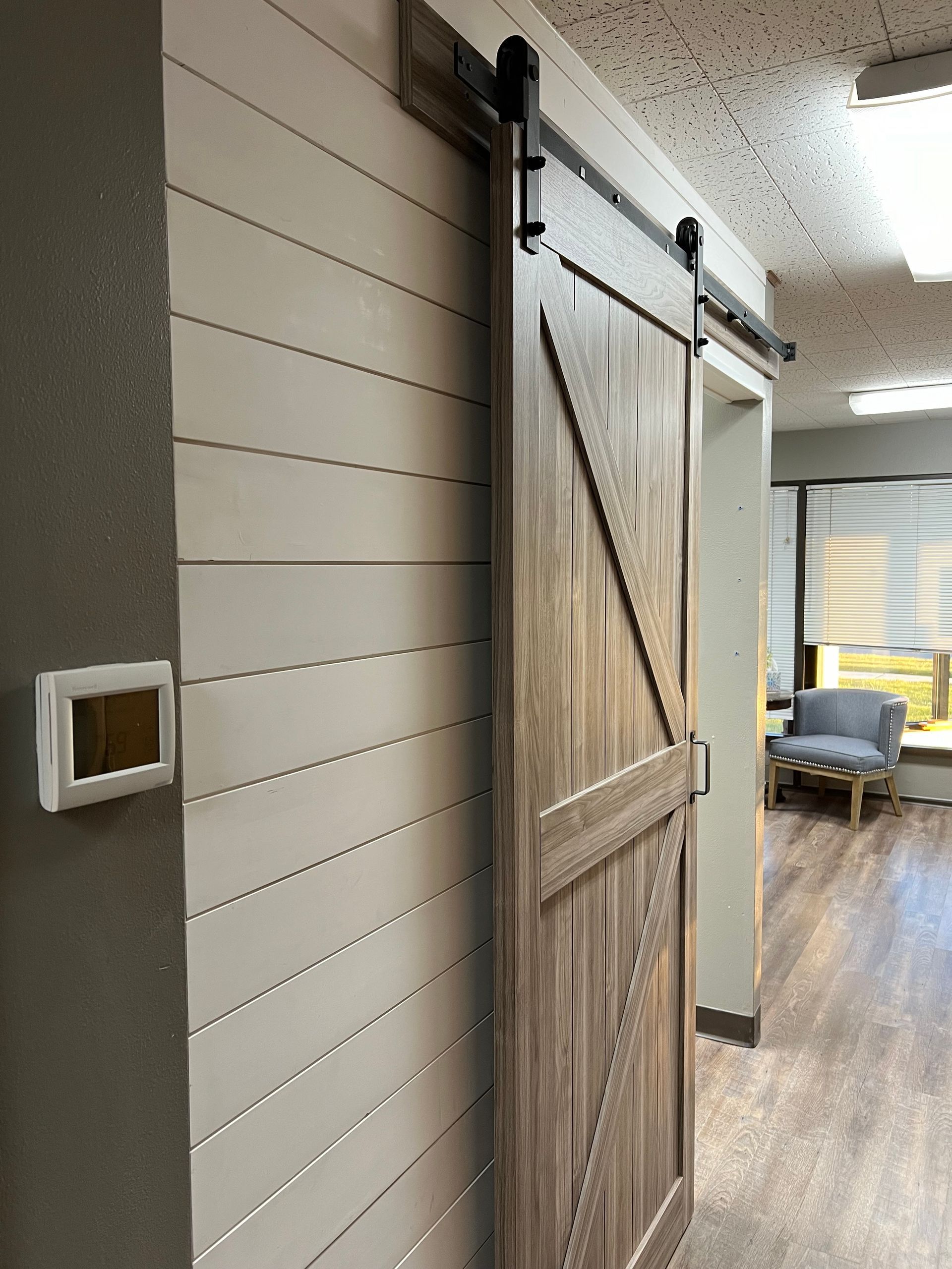 White door with wood trim and wainscoting, black doorknob, in a room with wood flooring.