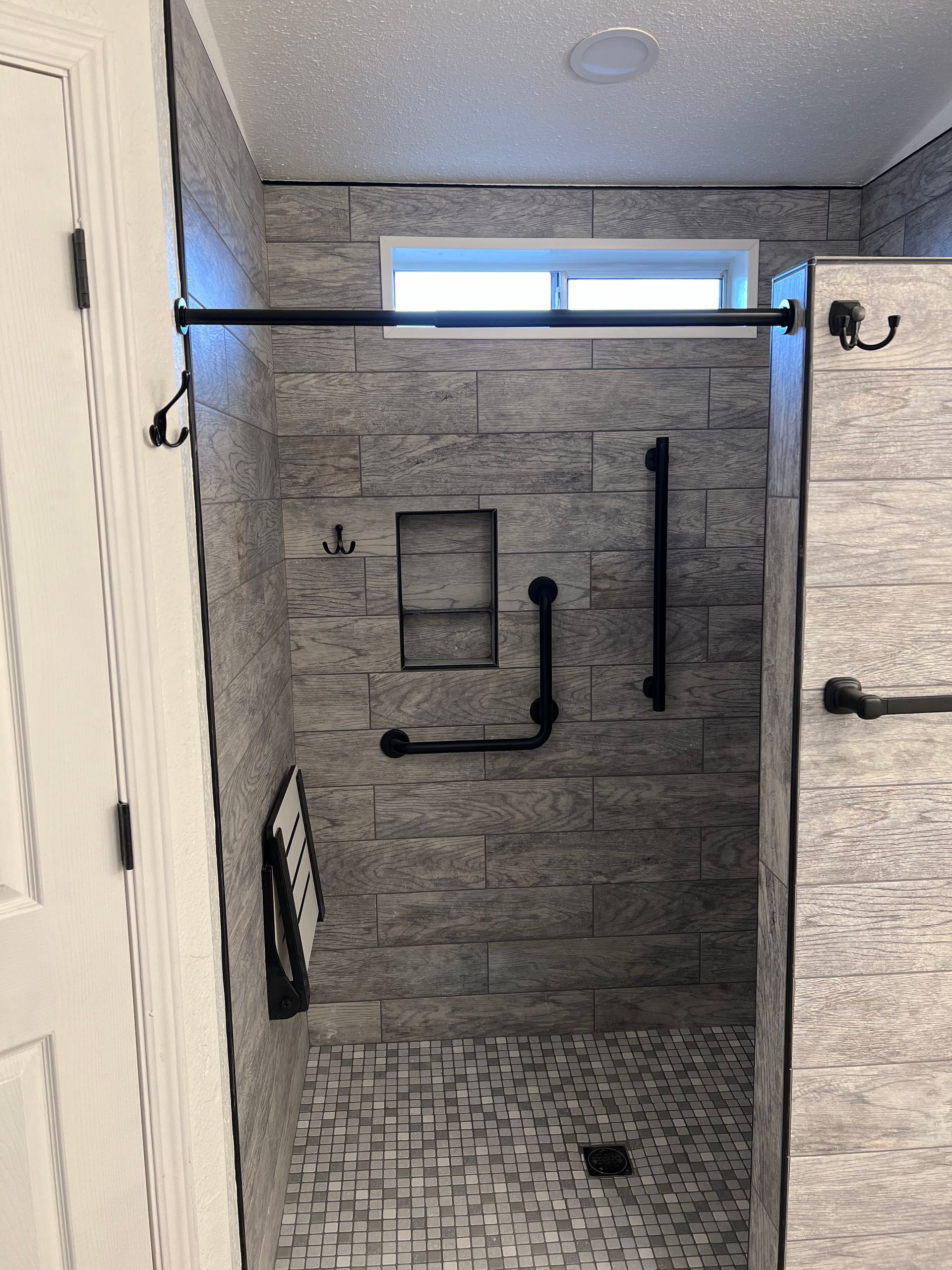 Bathroom with toilet, storage cabinet, and shower/tub. Gray walls and flooring.