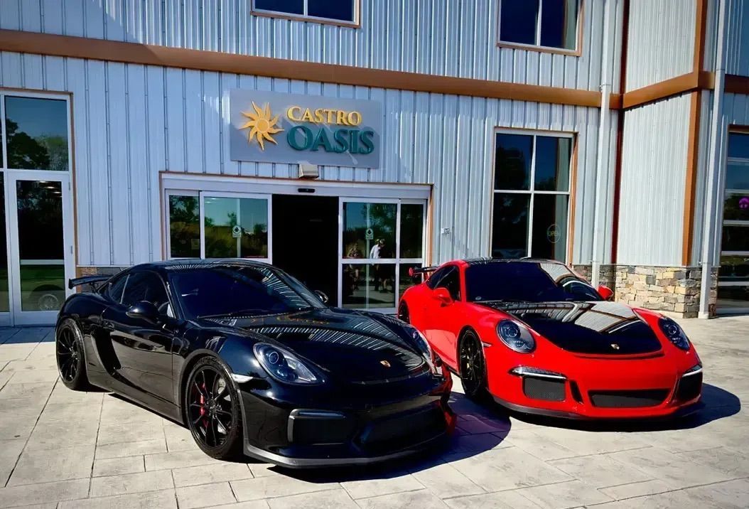 A black Porsche and a red Porsche parked side-by-side in front of a building with a