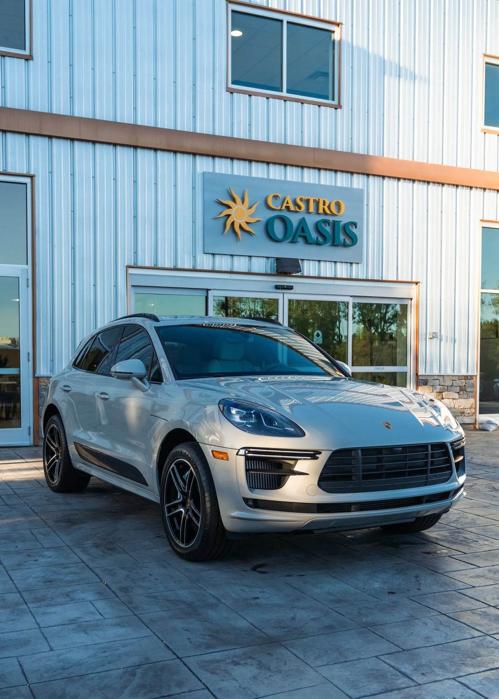 A silver Porsche SUV parked in front of a building with a 