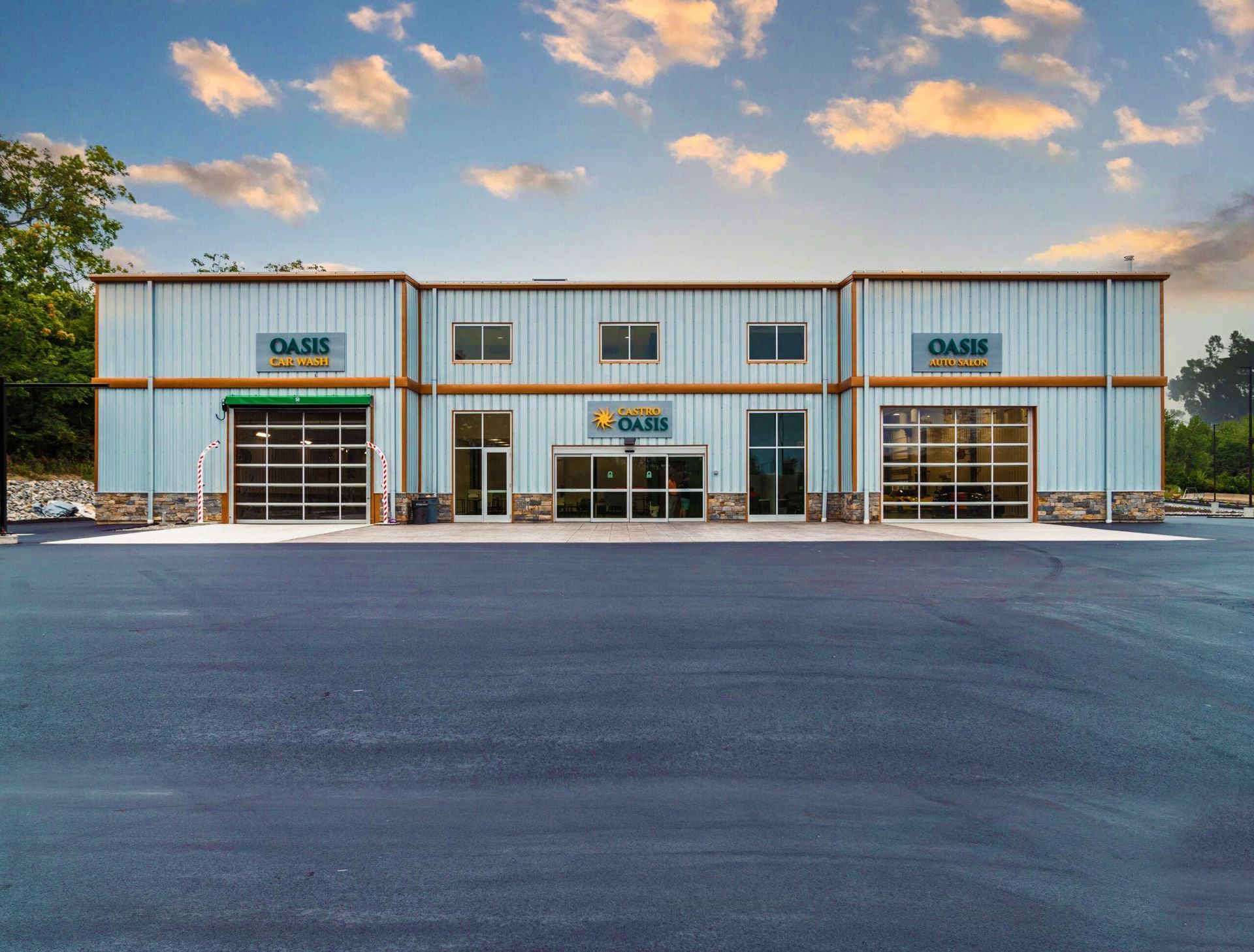 Wide-angle shot of a modern, light-blue metal warehouse building with three large garage-style doors and a central entrance.
