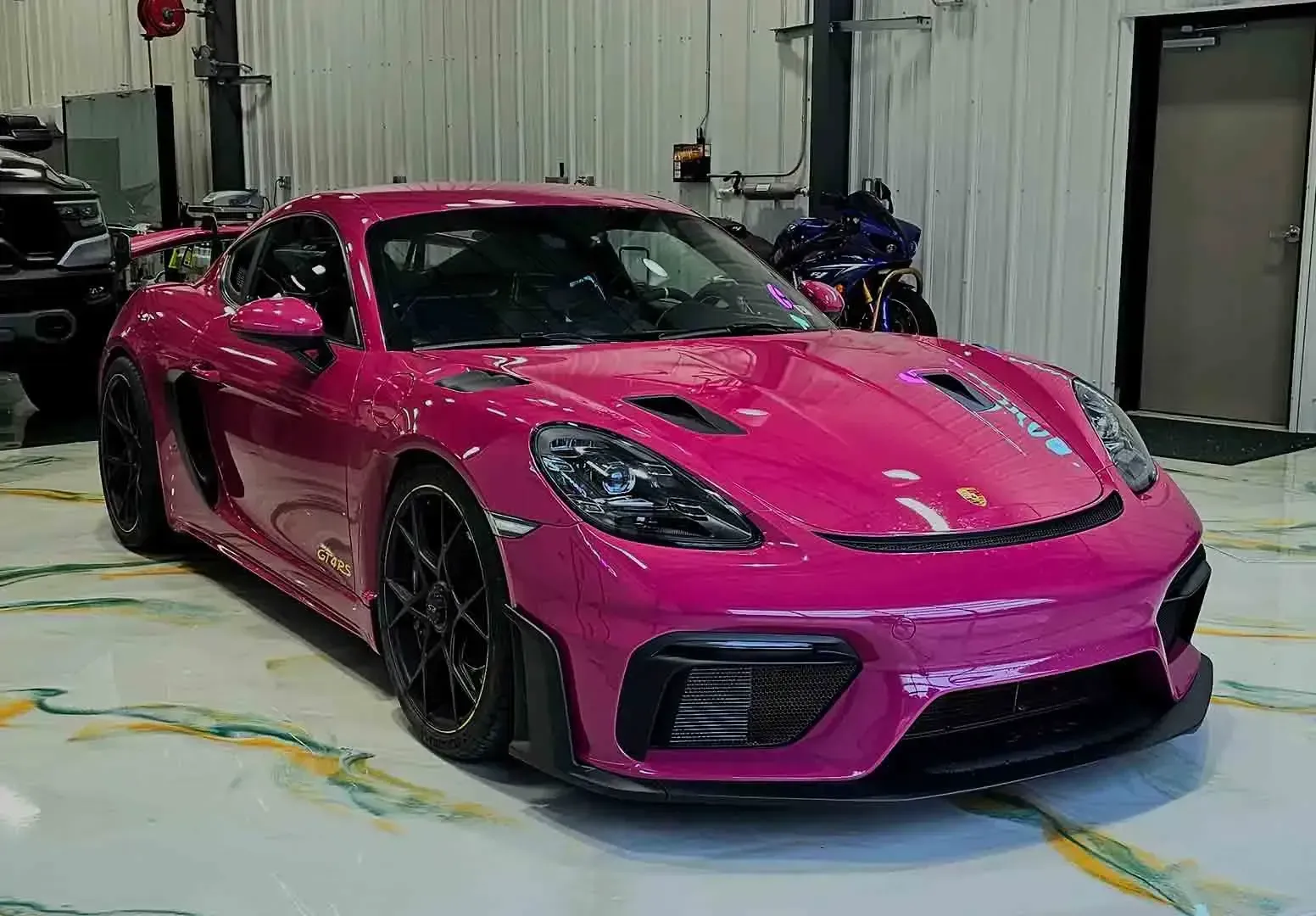 Bright pink sports car in a garage, viewed from the front-left side.