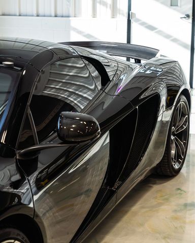 Black sports car in a showroom, shown from the front side with glossy reflective bodywork