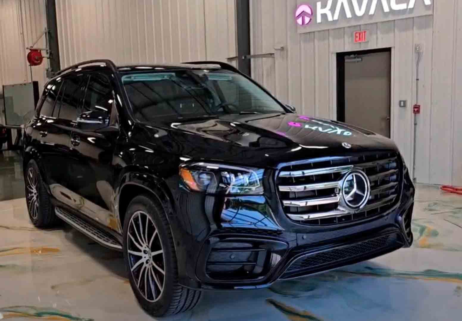A black Mercedes-Benz SUV parked inside a showroom with a Karvana sign on the wall.