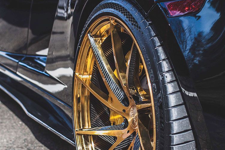 Close-up of a black sports car with gold rims and low-profile tires