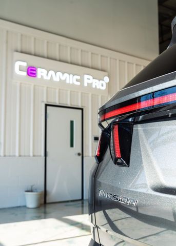 Ceramic Pro storefront with white paneled wall and partial close-up of a black vehicle
