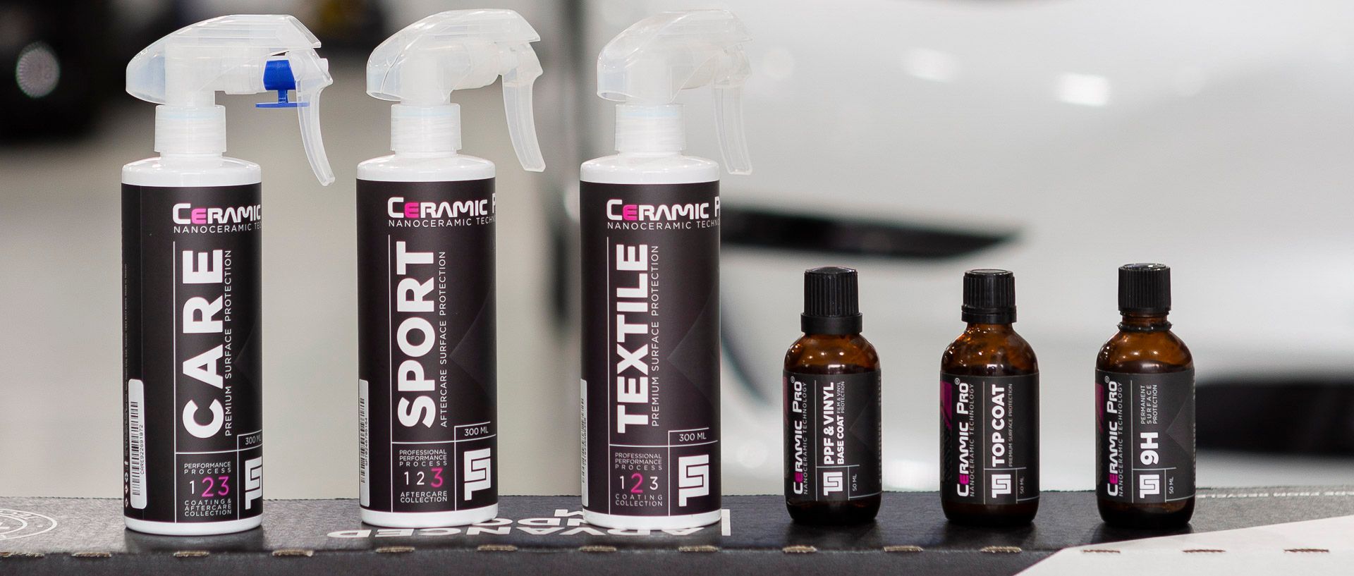 CLEAN CARE, SPORT, and TEXTILE spray bottles with small brown dropper bottles on a shelf