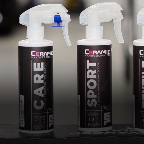 Three black and white spray bottles with trigger tops, labeled “Ceramic Care,” lined up on a shelf.