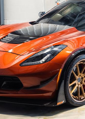 Orange sports car with black accents and gold wheels, shown in a showroom.