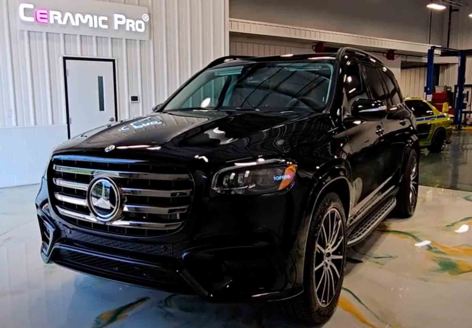 Black SUV in an auto detailing shop with a Ceramic Pro sign in the background