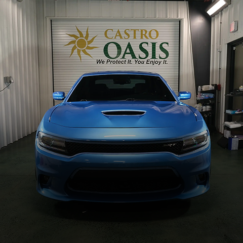 Blue sports car parked in a garage under a Castro Oasis sign