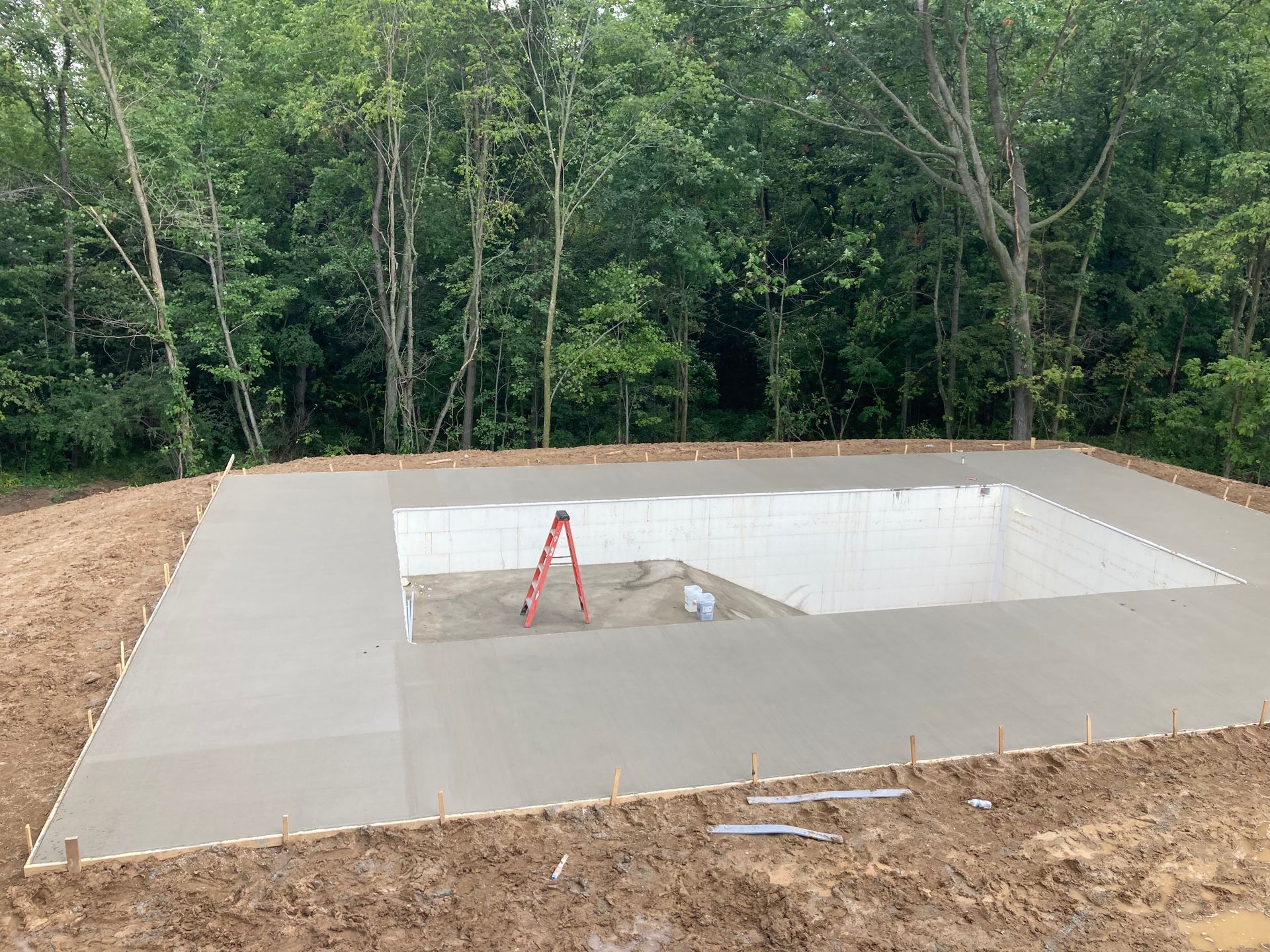 A large concrete pool is being built in the middle of a dirt field.