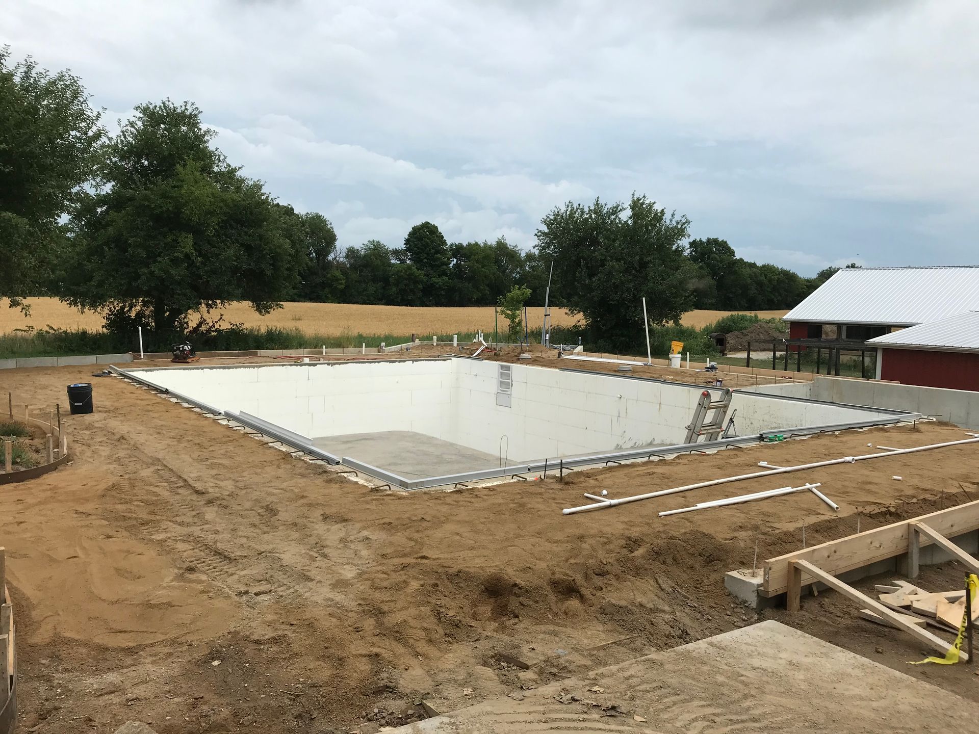 A large swimming pool is being built in a dirt field.