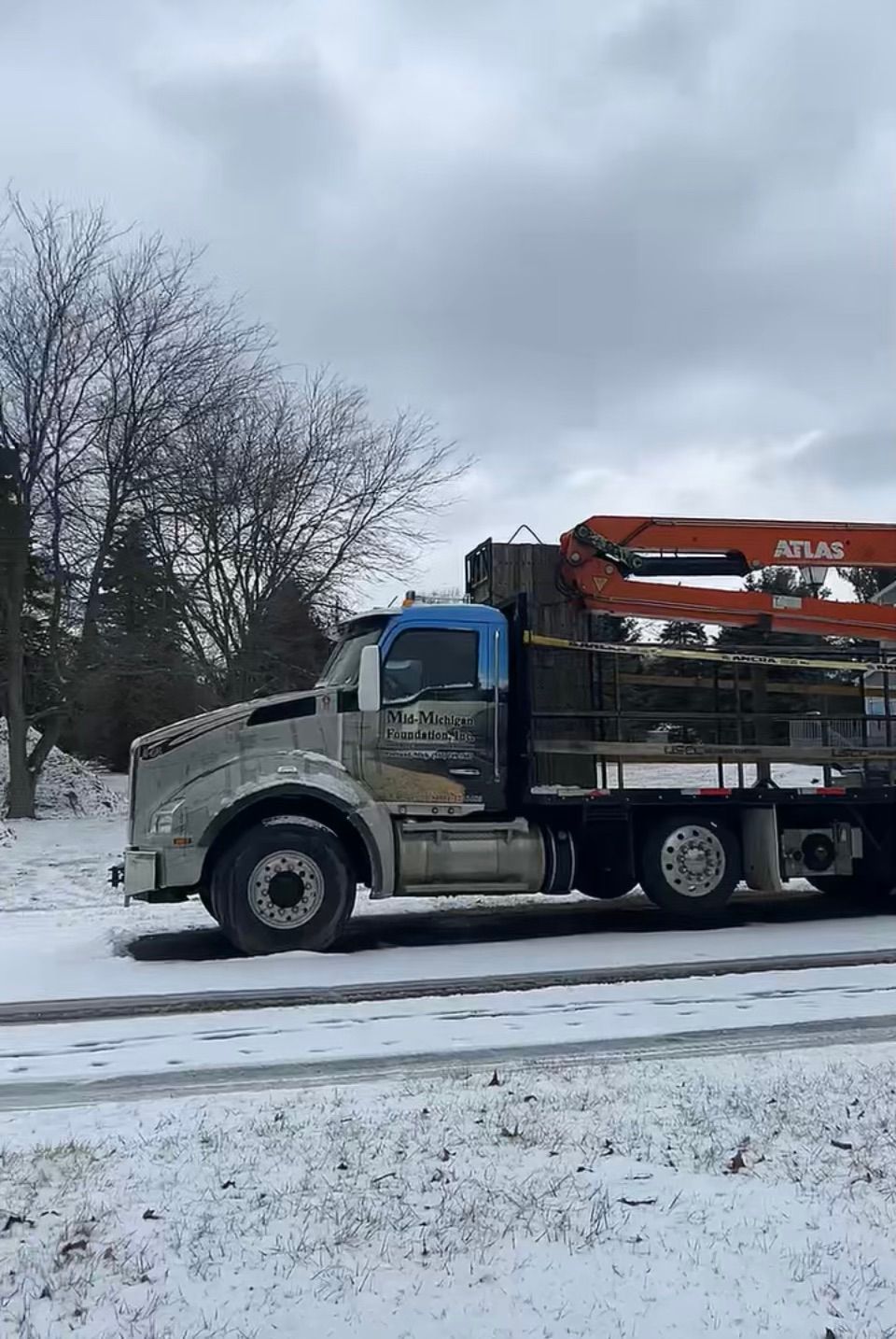 A semi truck is parked on the side of the road in the snow.