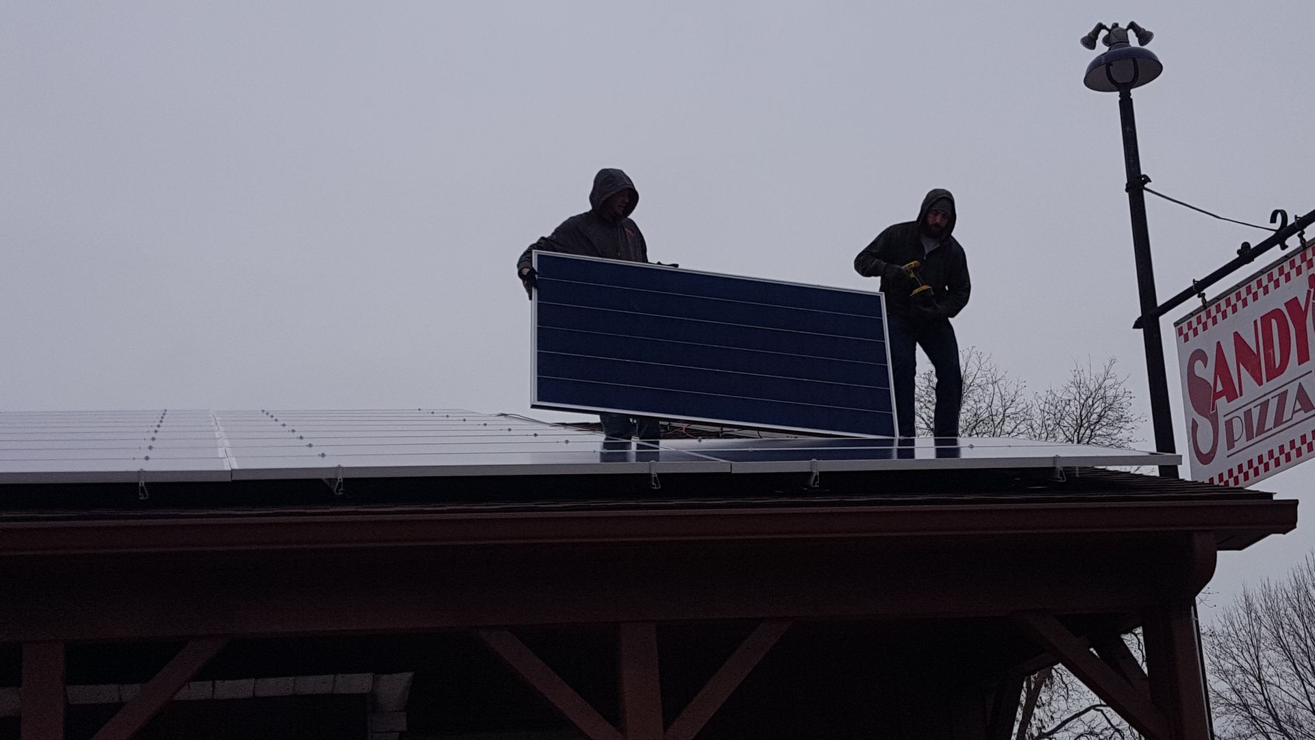 Two Morton Electric Workers are working on the roof installing a solar panel