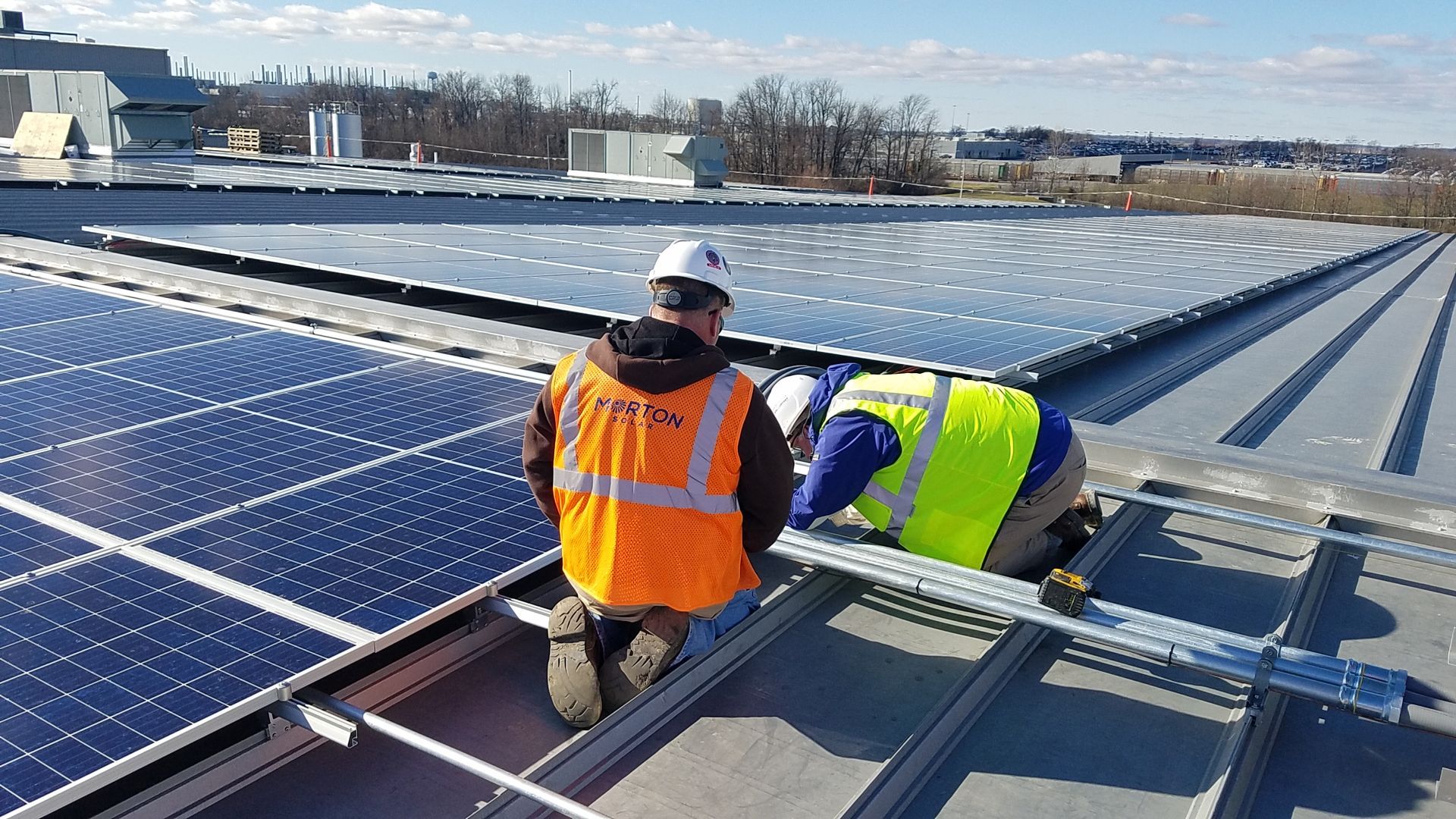 A man is installing solar panels on a roof.