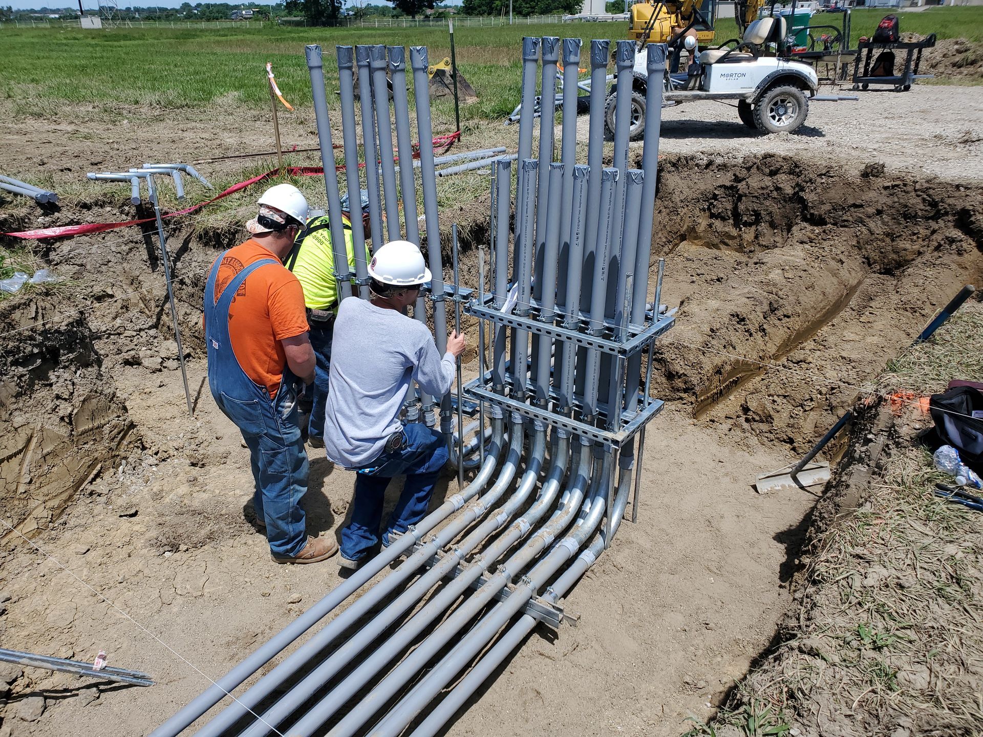 Two Morton Electric workers are installing metal rods for the construction of a electrical panel.