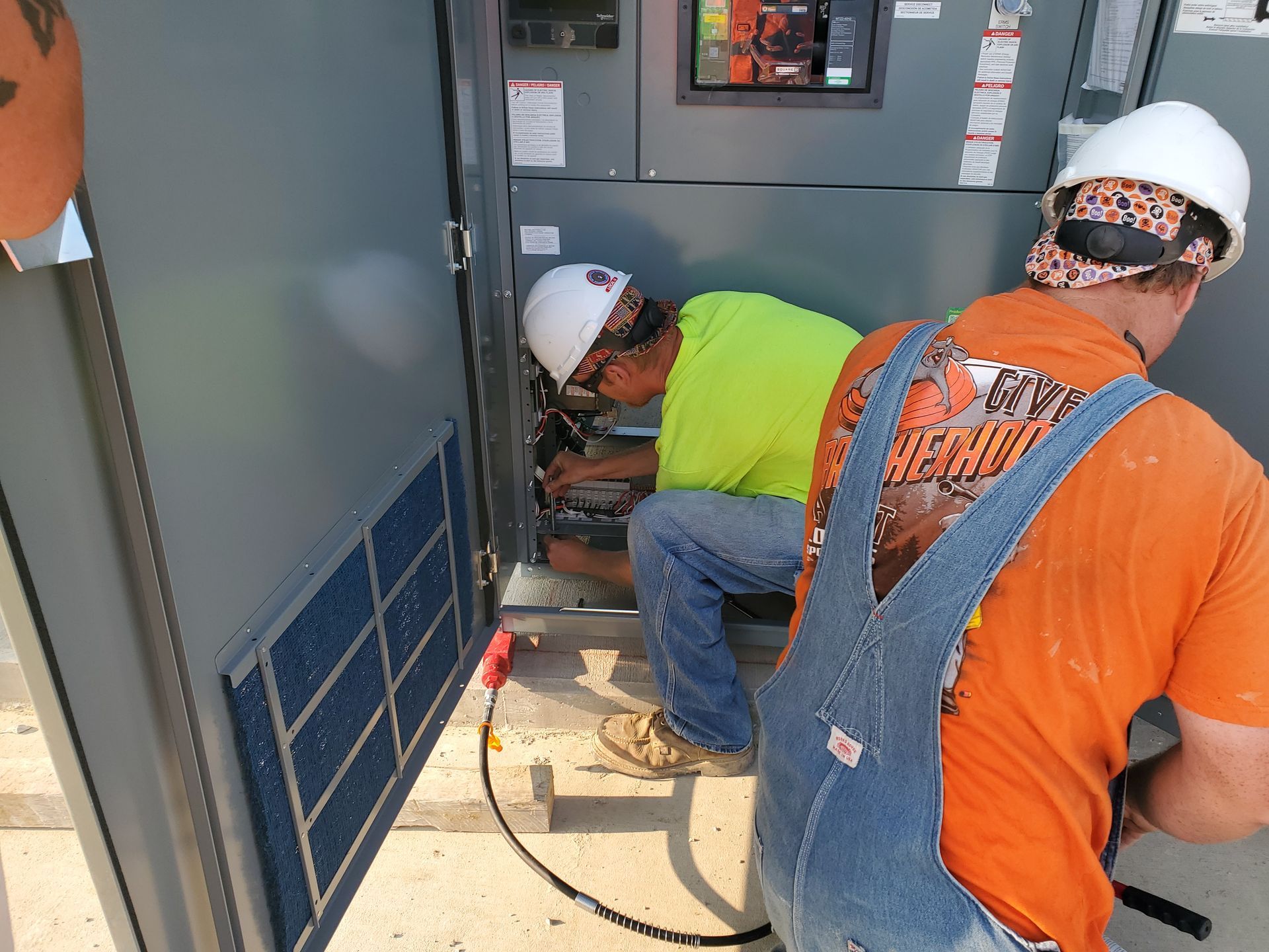 Two Morton Electric workers are installing an electrical panel.