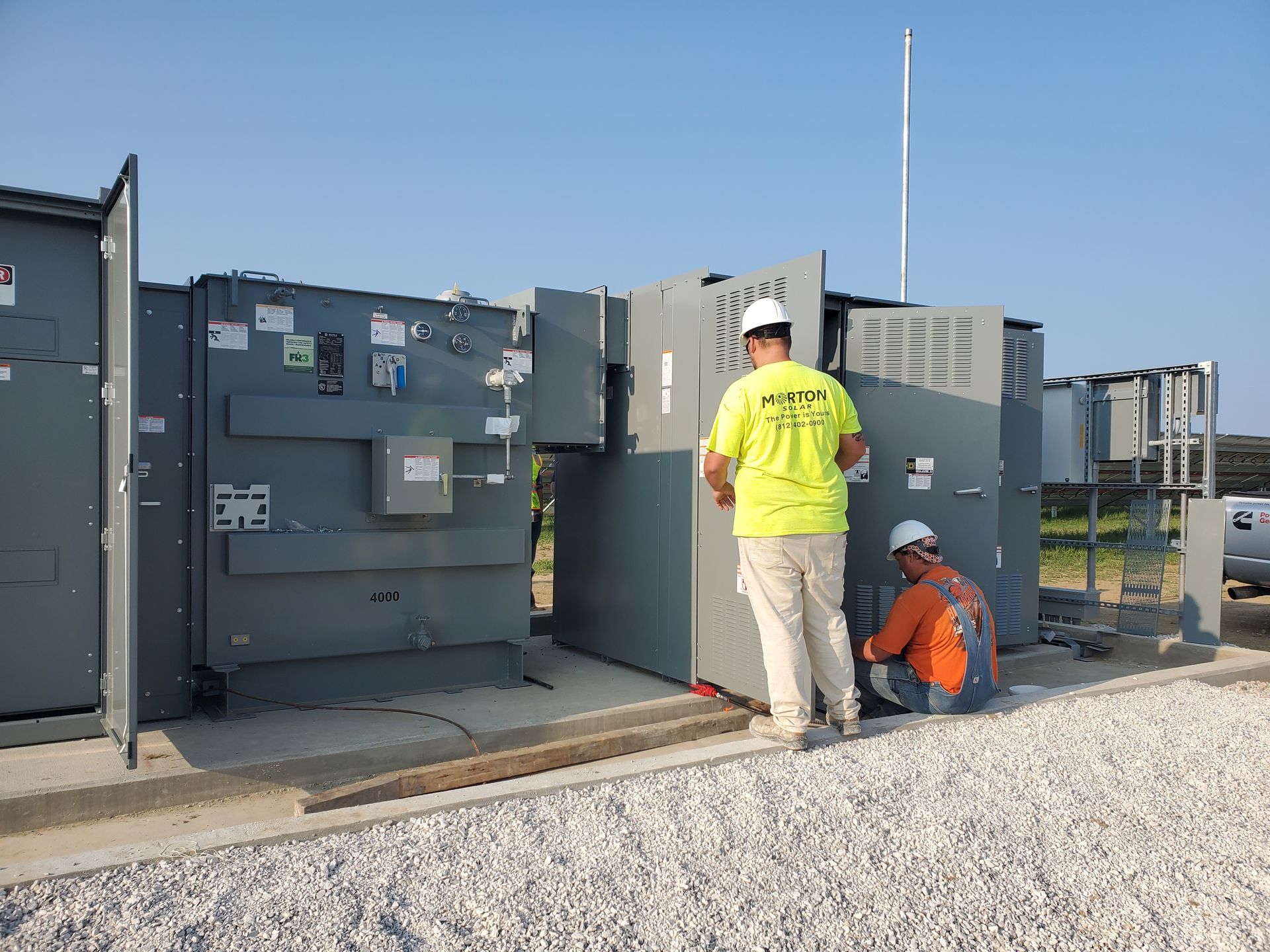 Two Morton Electric workers are installing an electrical panel.