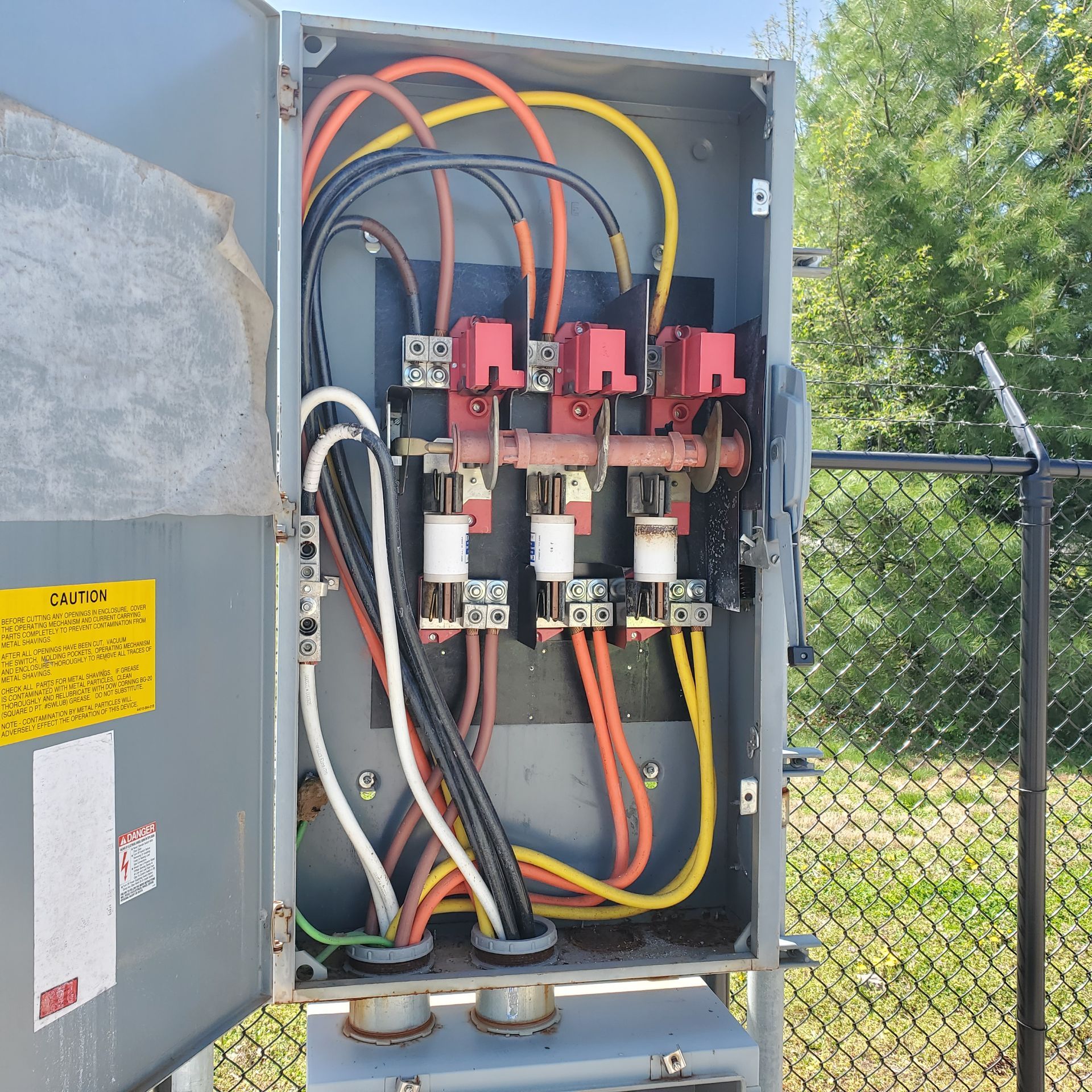 Electrical panel junction box with circuit boards, wires, and connectors, mounted outdoors.