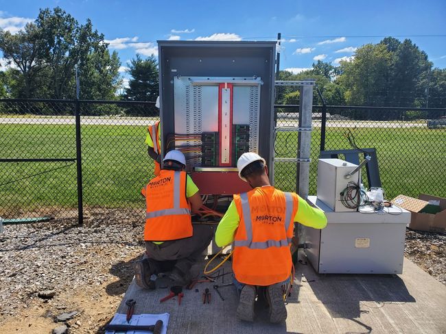 Two Morton Electric workers are working on a power box