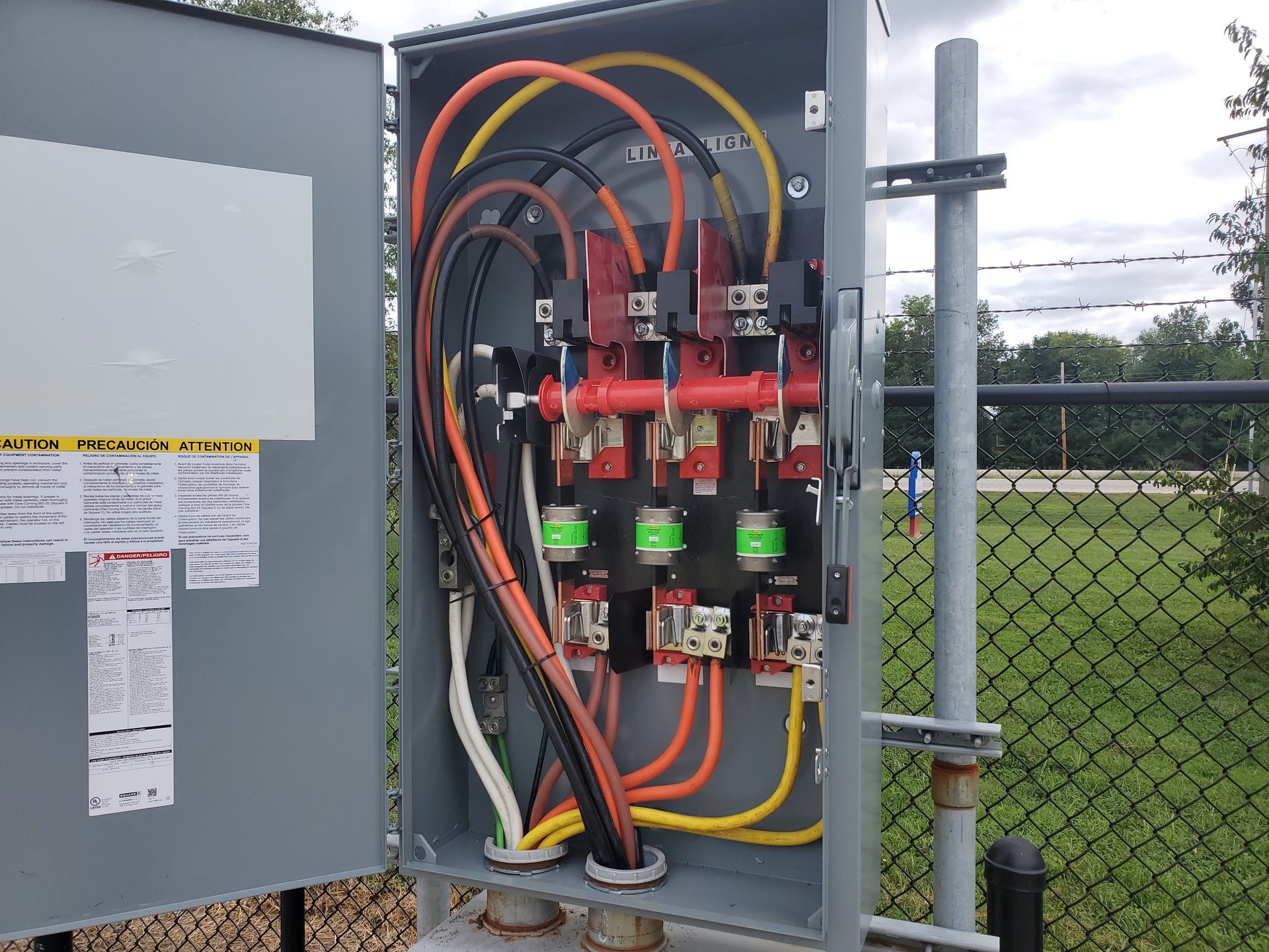 Electrical panel junction box with circuit boards, wires, and connectors, mounted outdoors.