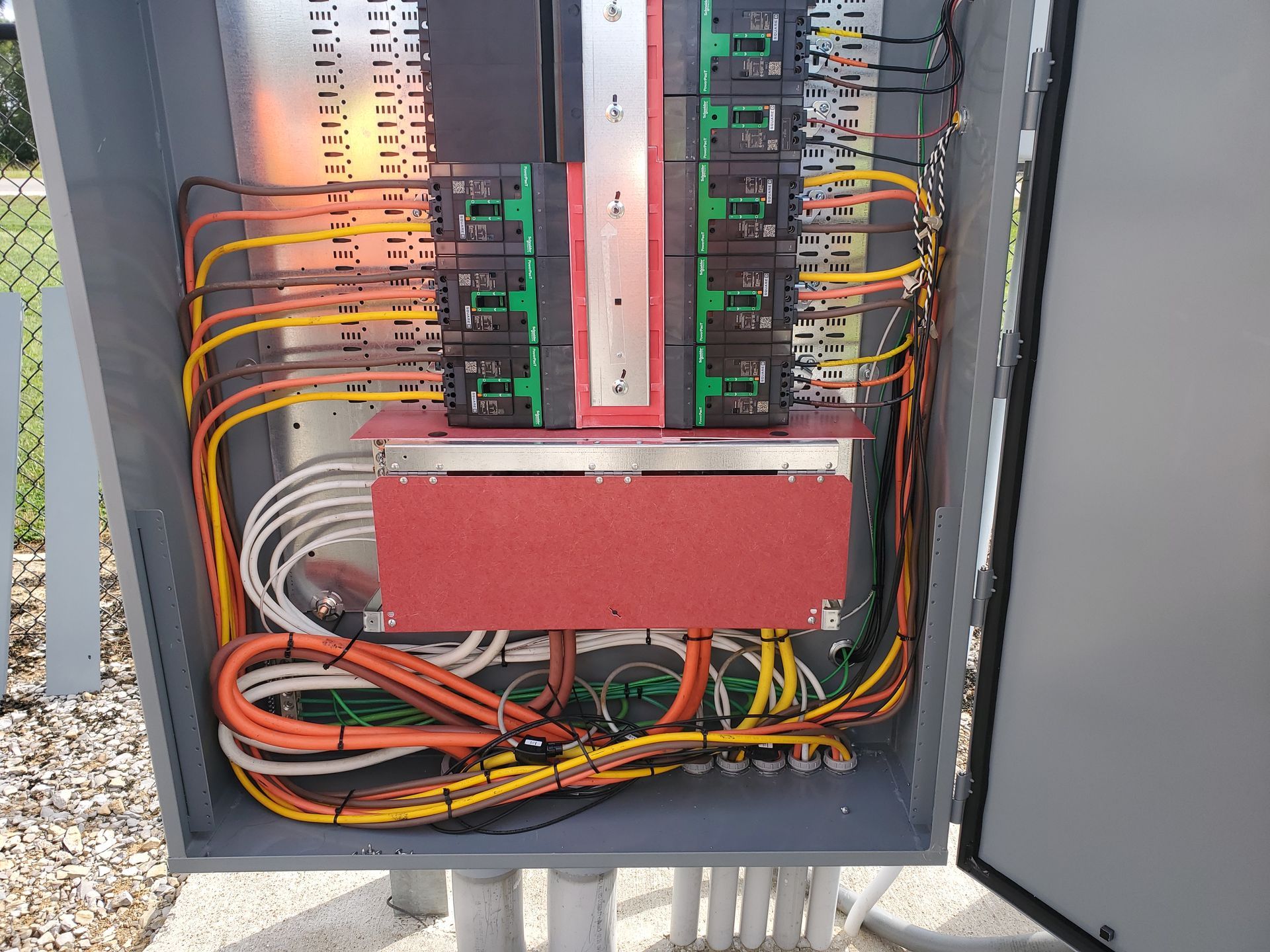 Electrical panel junction box with circuit boards, wires, and connectors, mounted outdoors.