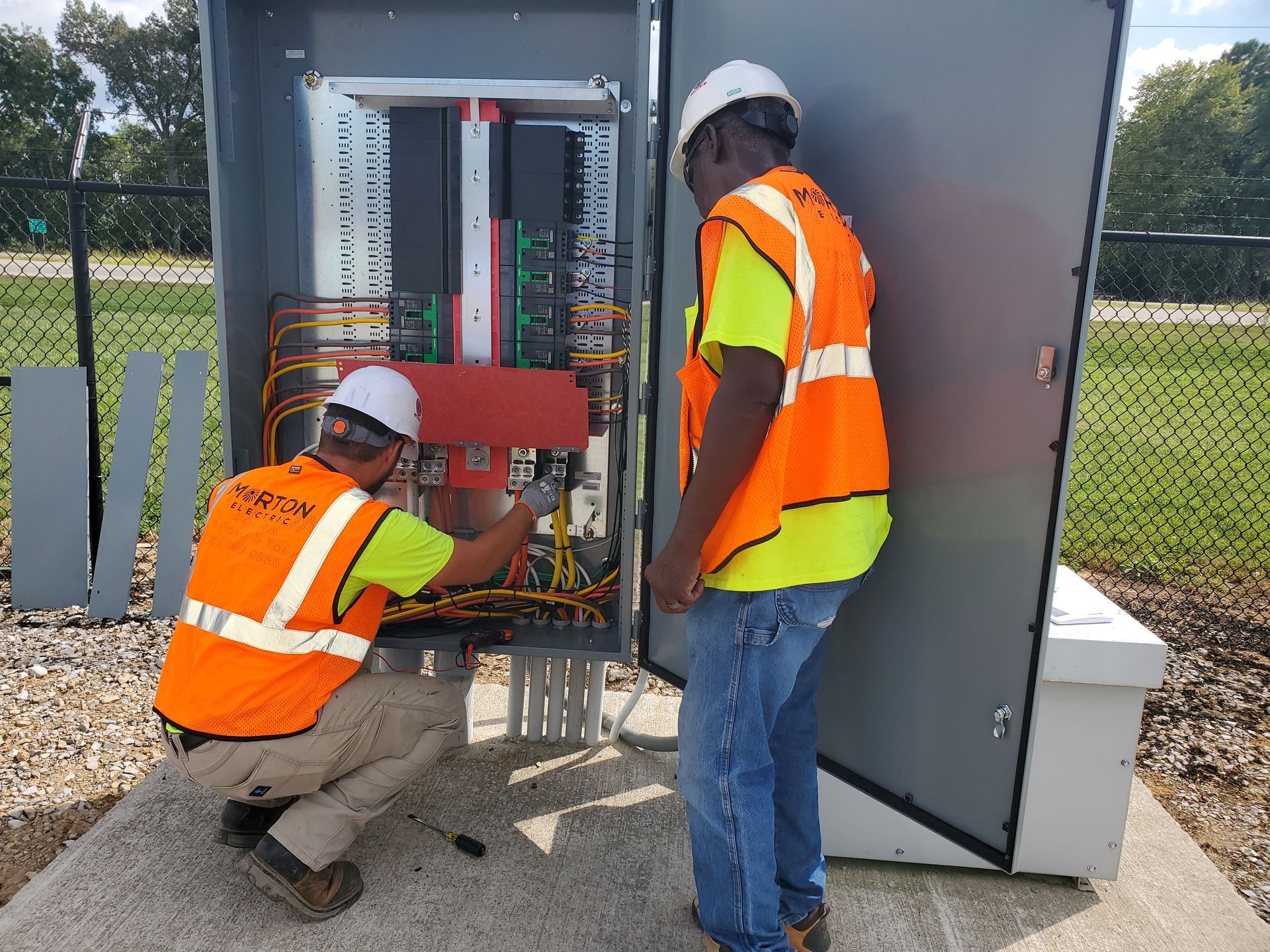 Two Morton Electric workers are installing electrical wiring in the electrical system.