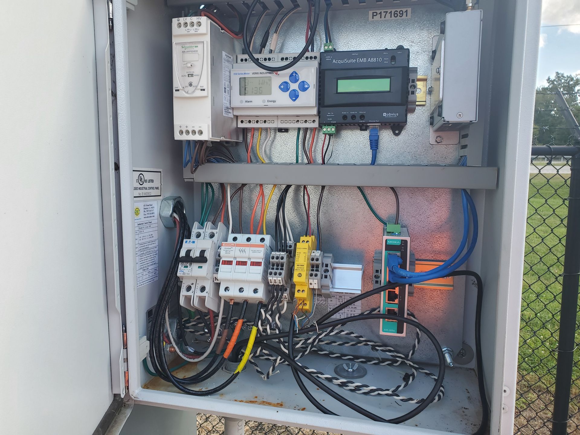 Electrical panel junction box with circuit boards, wires, and connectors, mounted outdoors.