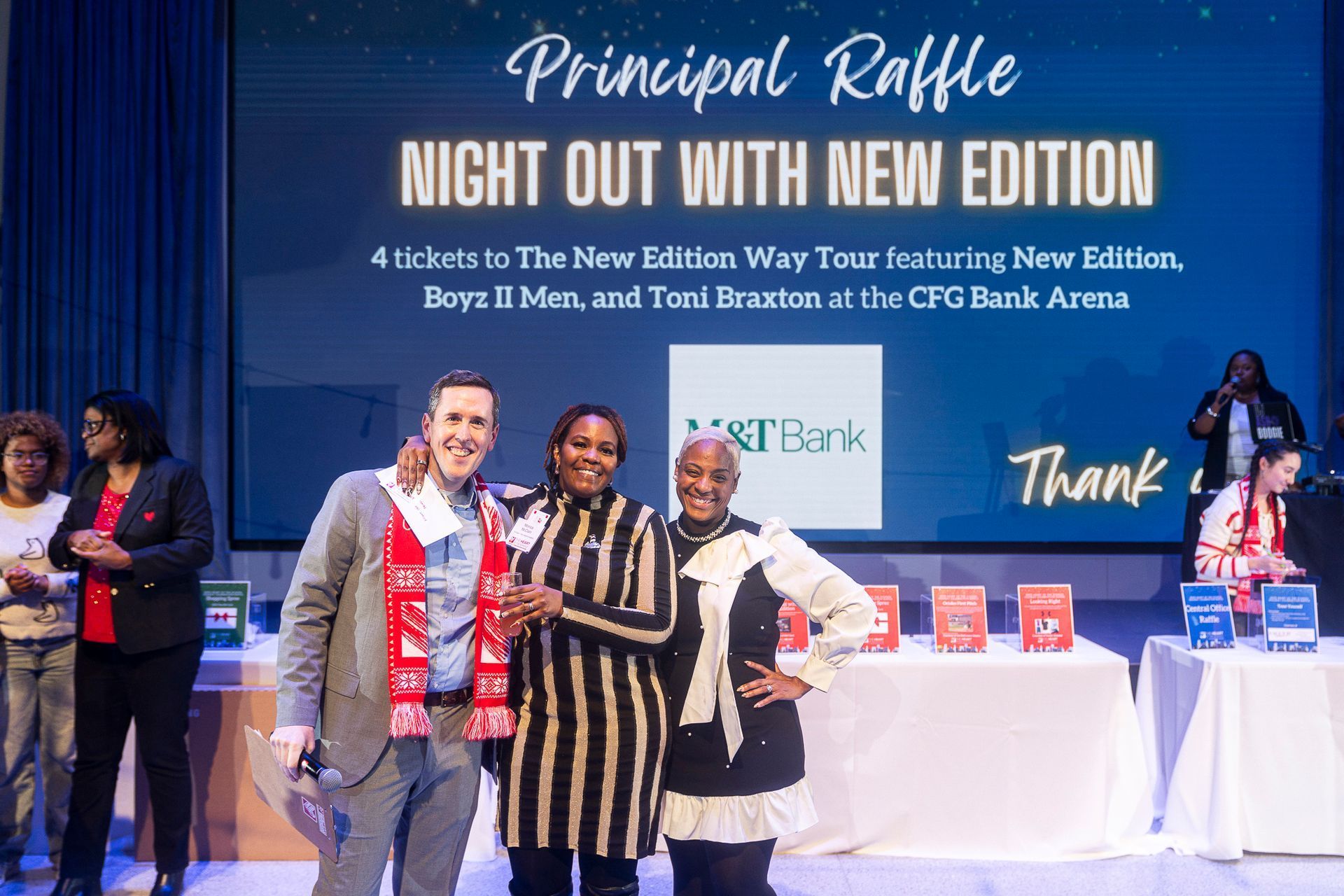 HOS Holiday Celebration - People on stage at a fundraising event, celebrating a raffle prize. A sign advertises