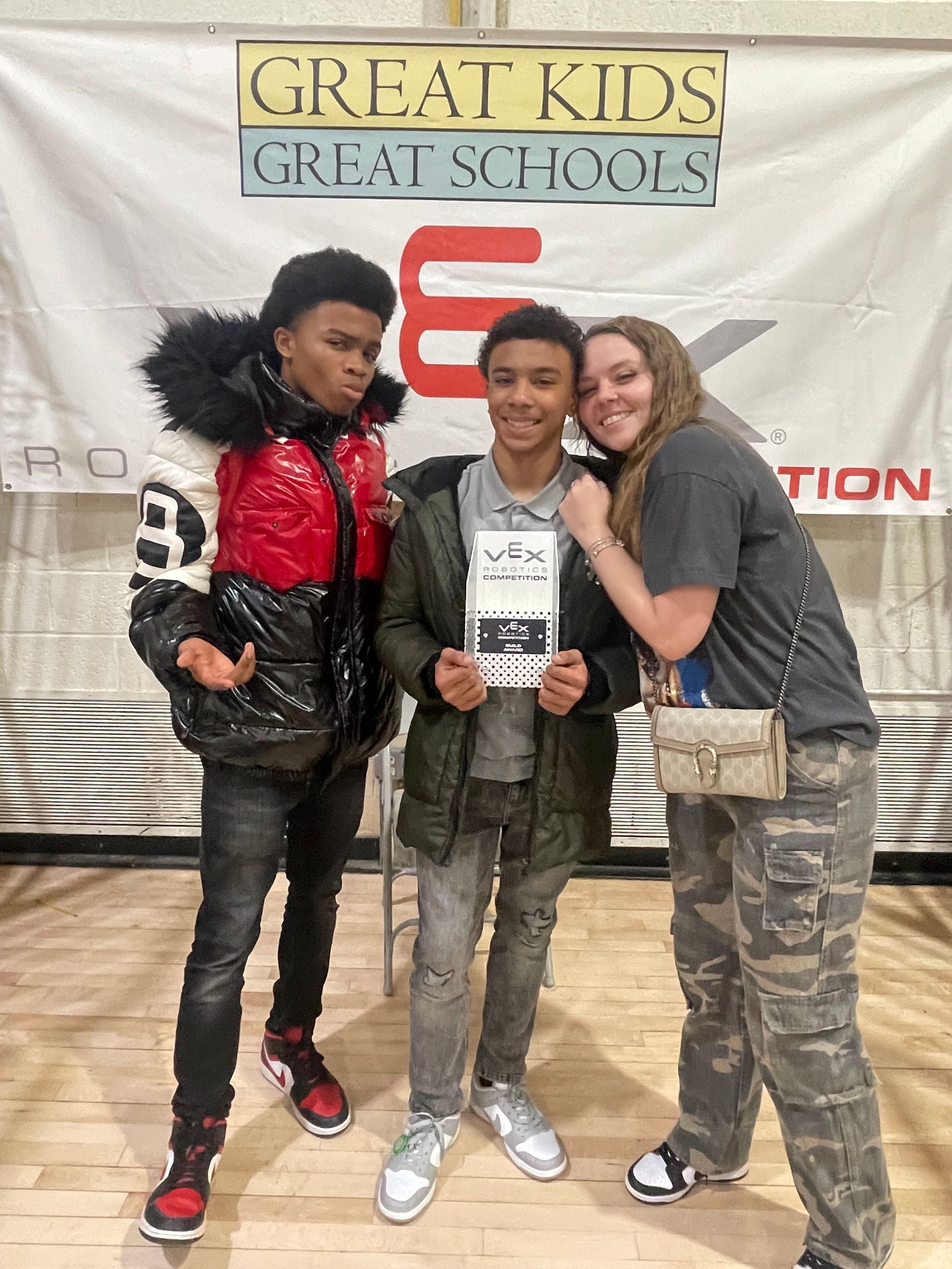 Hazelwood Elementary students pose for photo: boy holding a certificate, flanked by two others. Banner reads “Great Kids Great Schools.”