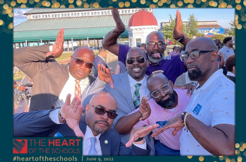 Heart of Schools Honros - Group of men posing playfully outdoors. Some have hands up, one sticking out tongue. Event setting.