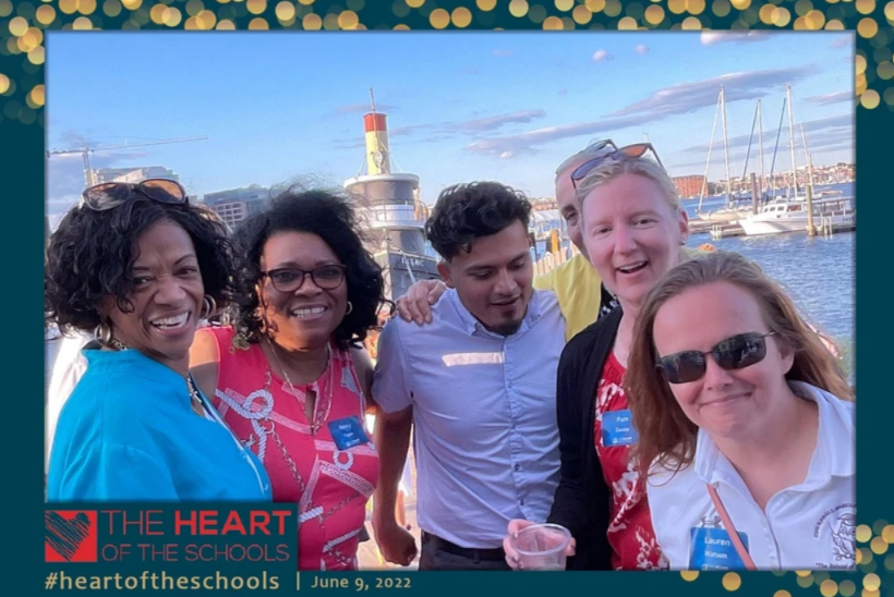 HOS Honros - Group of people smiling near water, lighthouse in background, photo-booth style.
